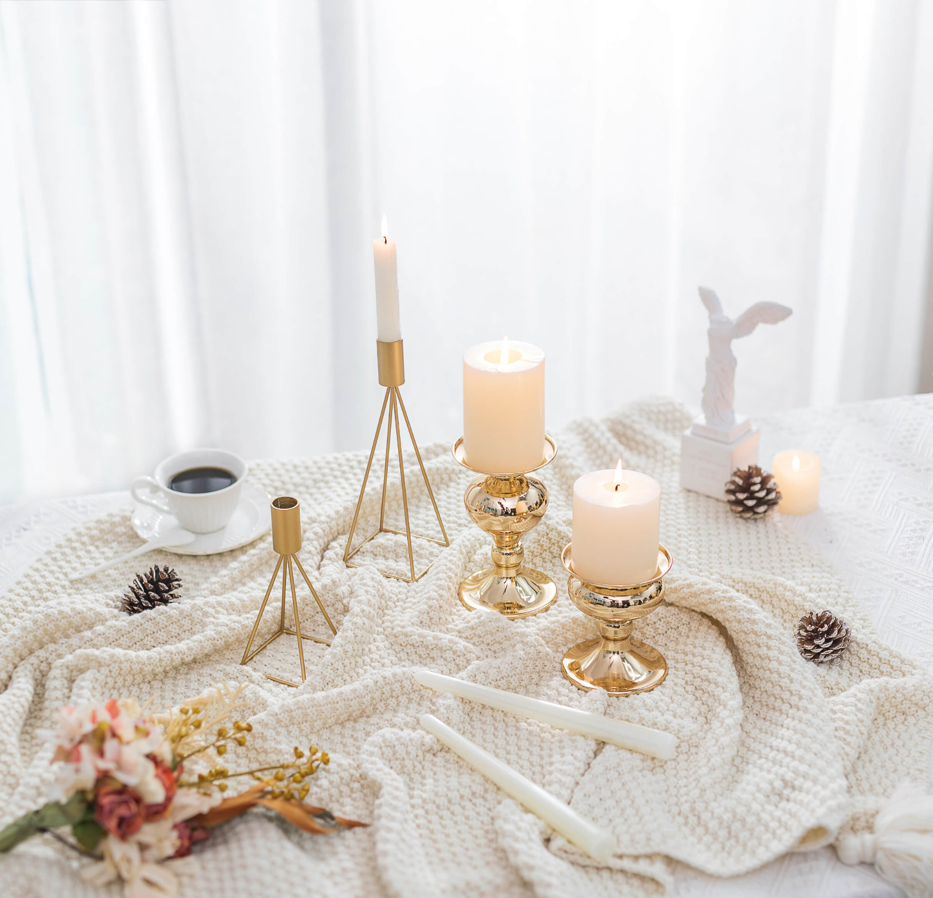 Ivory knitted throw styled with gold candle holders, pillar candles and dried flowers